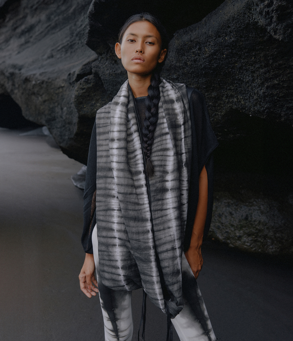 omen standing in front of a black rock wearing a black and white tie dye linen infinity scarf.