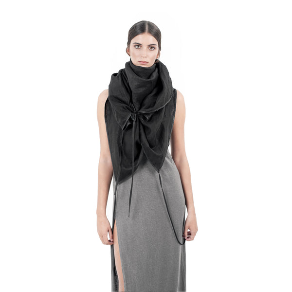 women wearing a black linen shawl with leather tassels wrapped around her neck.